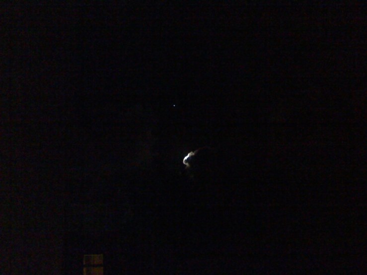 the moon behind the edge of a cloud